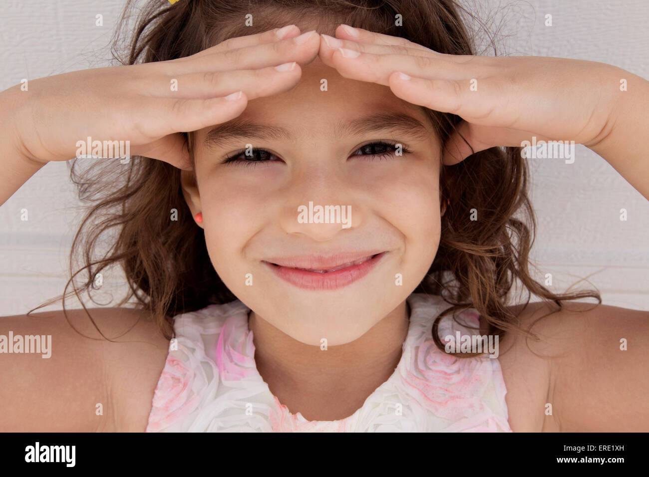 Smiling Hispanic girl ombrage les yeux du soleil Banque D'Images