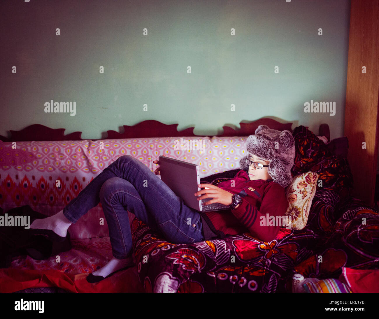 Mixed Race boy wearing fur hat sitting on sofa Banque D'Images
