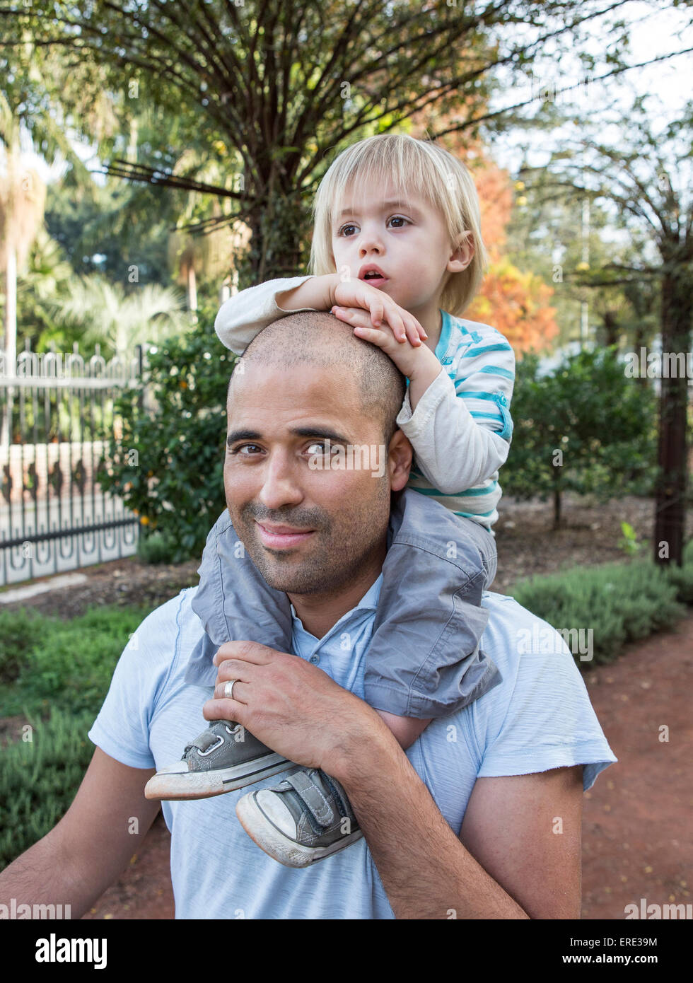 Hispanic father carrying son on shoulders in park Banque D'Images