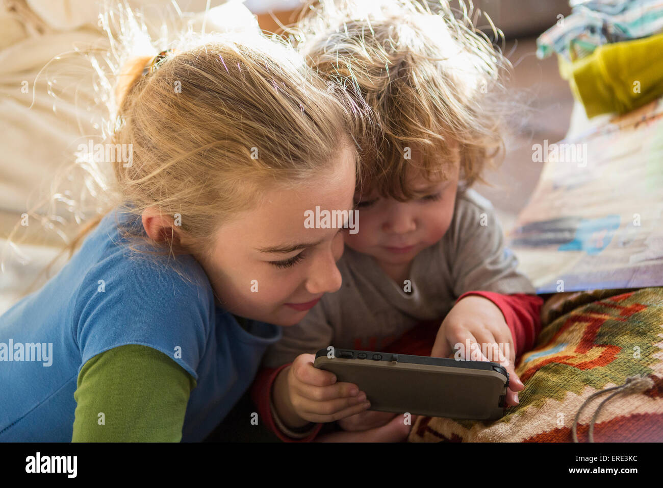 Frère et soeur de race blanche using cell phone on sofa Banque D'Images
