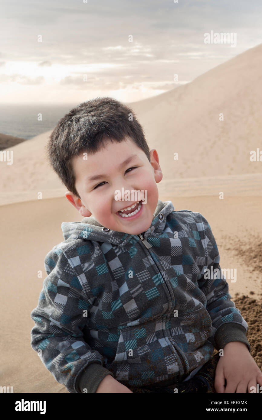 Hispanic boy smiling on sand dune on beach Banque D'Images