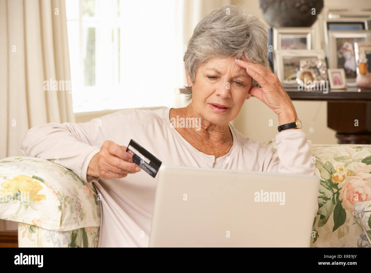 Frustré a pris sa retraite Senior Woman Sitting on Sofa At Home Using Laptop Banque D'Images Frustré a pris sa retraite Senior Woman Sitting on Sofa At Home Using Laptop Banque D'Images