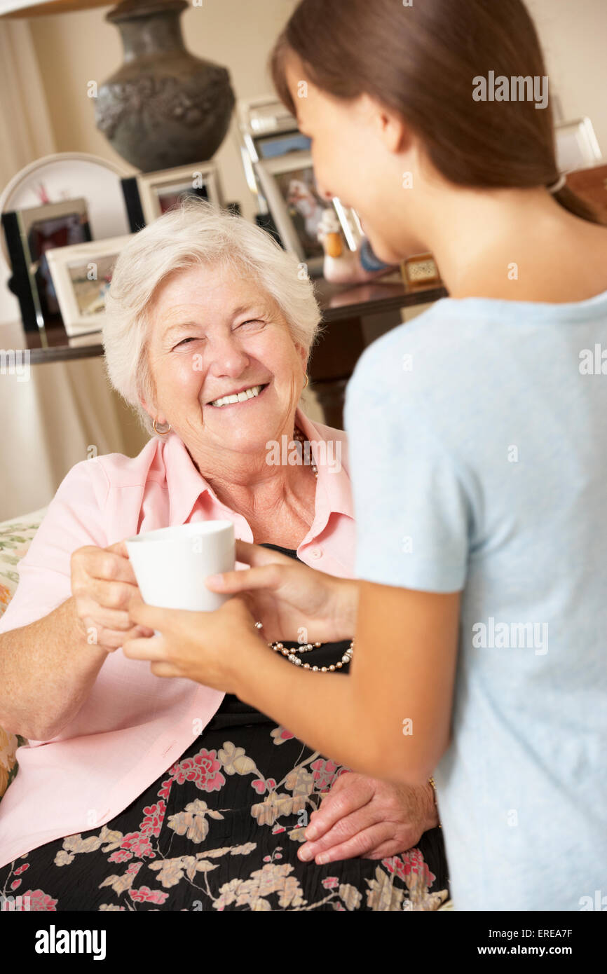 Teenage Granddaughter faire grand-mère boisson chaude à la maison Banque D'Images
