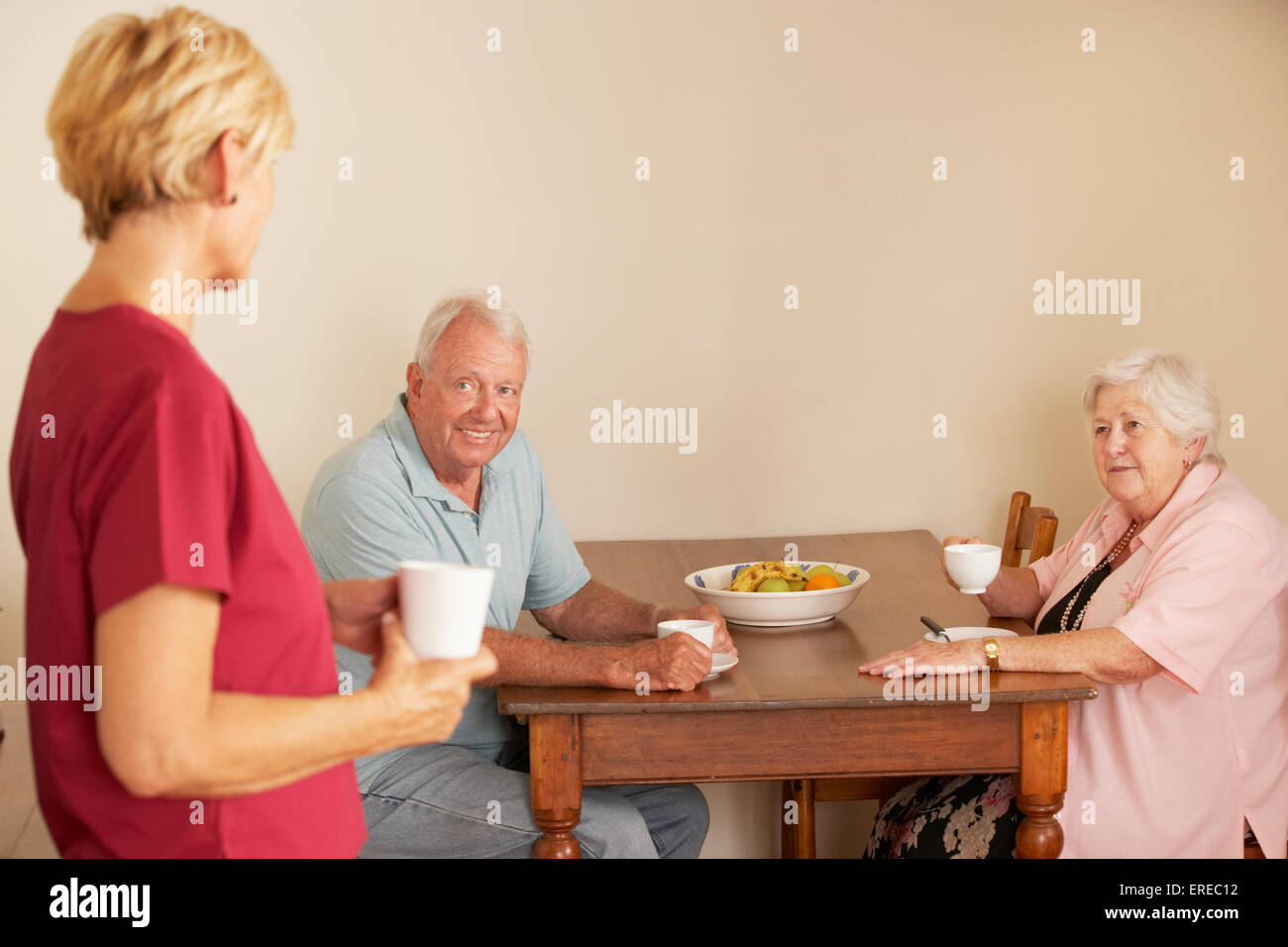 Accueil Aider à partager une tasse de thé avec Senior Couple In Kitchen Banque D'Images