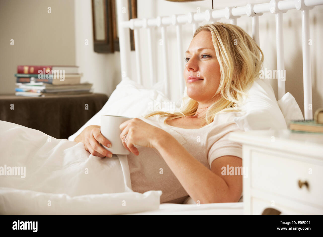 Woman Relaxing In Bed avec boisson chaude Banque D'Images