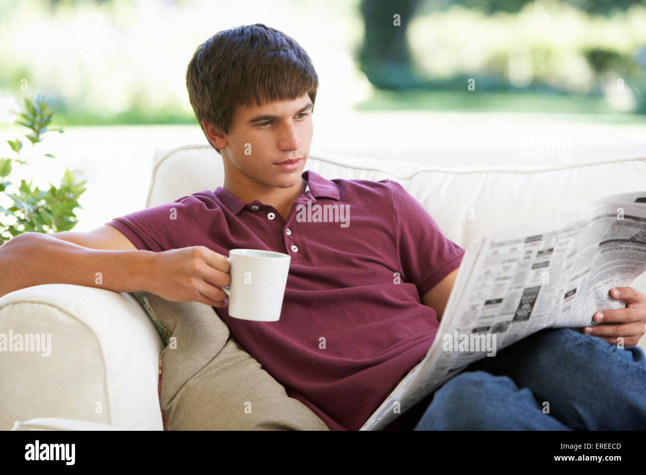 Woman Relaxing On Sofa avec du papier journal et de verre Banque D'Images