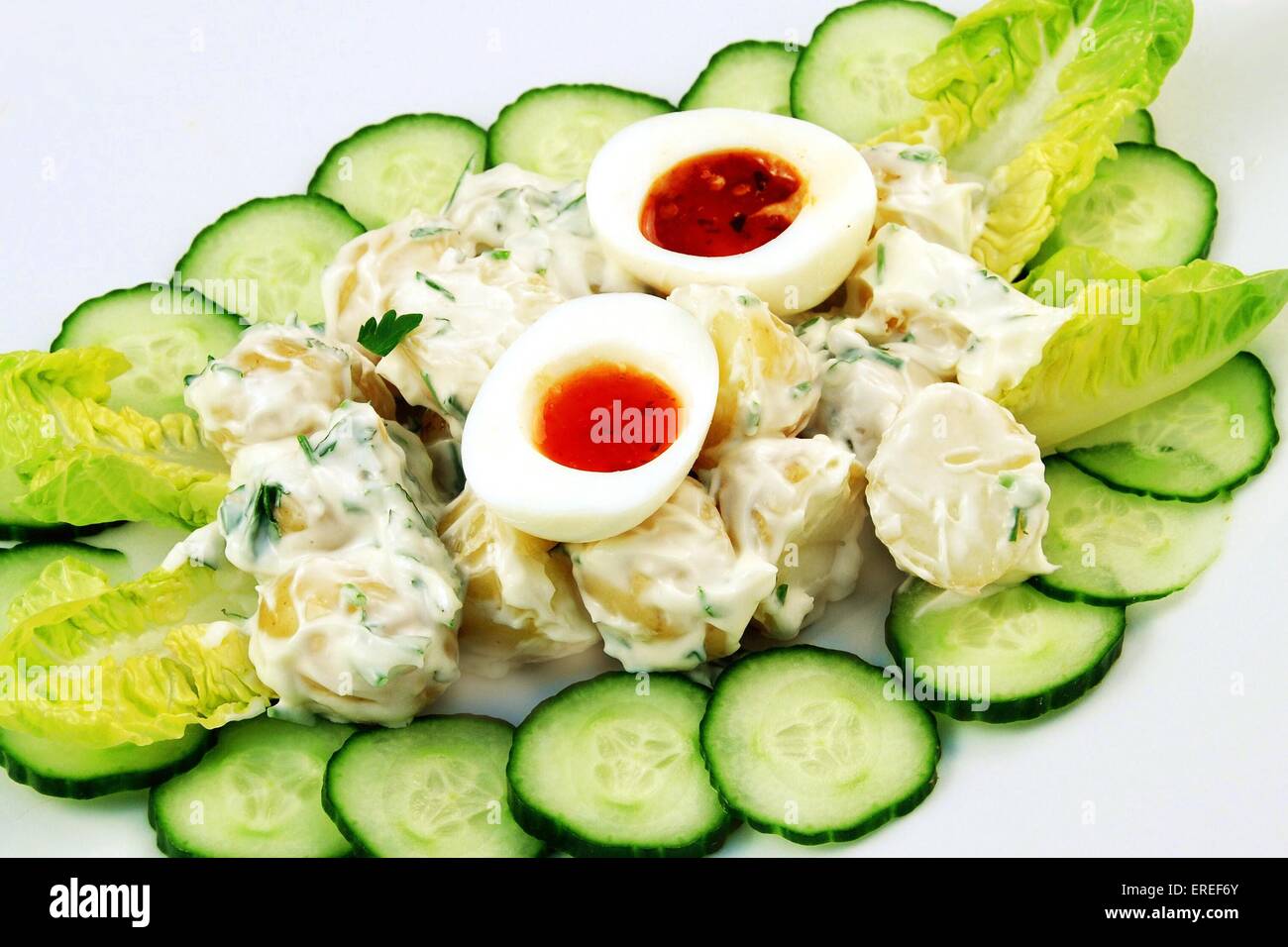 Salade de pommes de terre avec une mayo surround de concombre et laitue croustillante surmontée avec oeuf mollet de moitié et rempli de sauce au piment fort Banque D'Images