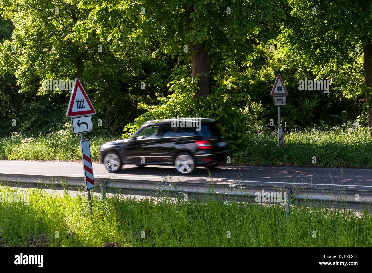 Route de campagne avec voiture passant et les signes d'un passage à niveau fermé à gauche, de l'Allemagne. Banque D'Images