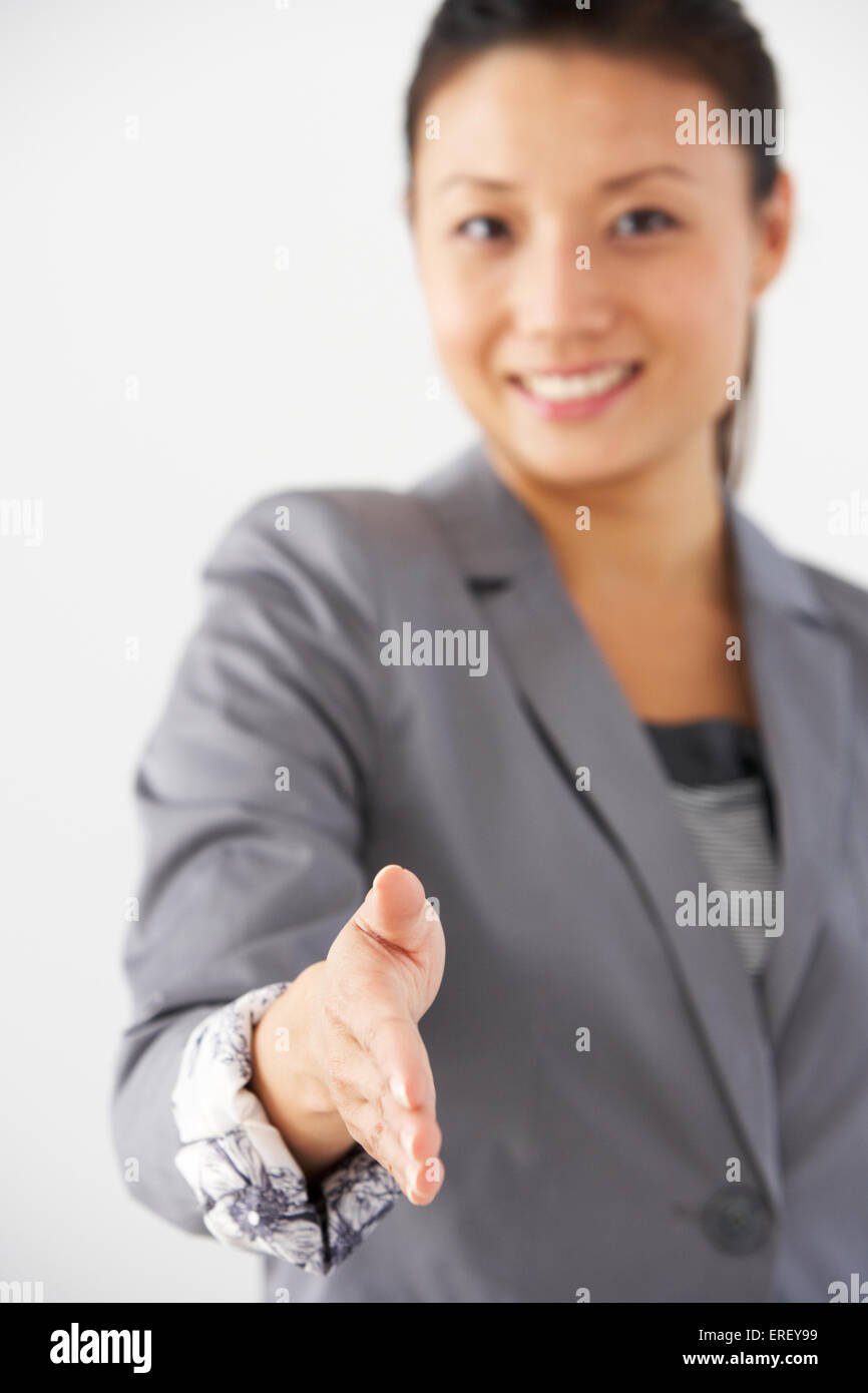 Studio Portrait Of Businesswoman Reaching Out pour serrer la main Banque D'Images