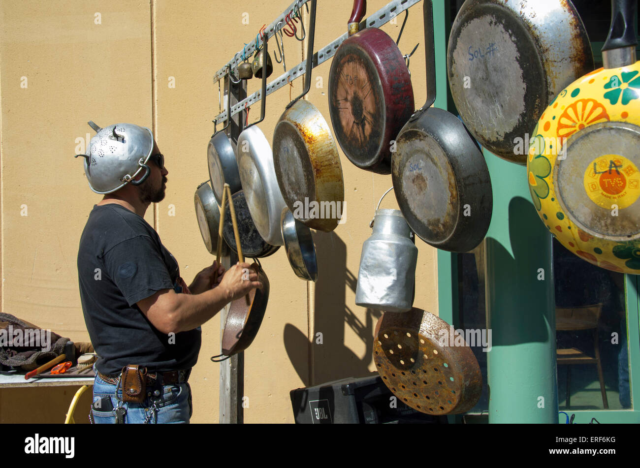 Homme jouant de la percussion d'écoute composée de poêles à frire dans le cadre d'une exécution par un groupe composé d'instruments Banque D'Images