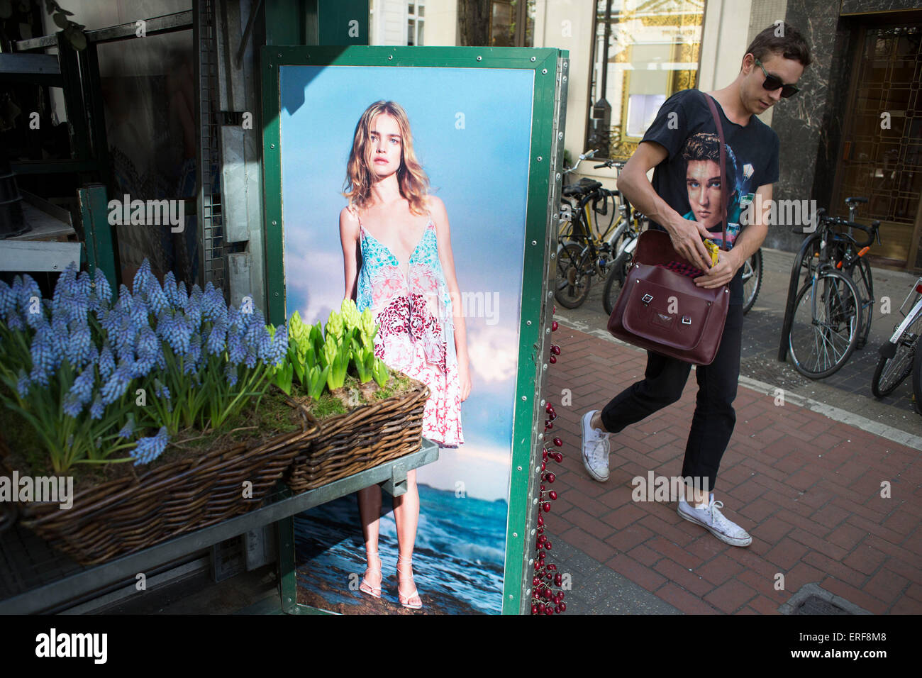 Photographie d'un modèle dans une robe d'été en interaction avec passant par le port d'un t-shirt Elvis Presley au Stella McCartney flower stall sur New Bond Street, London, UK. Banque D'Images