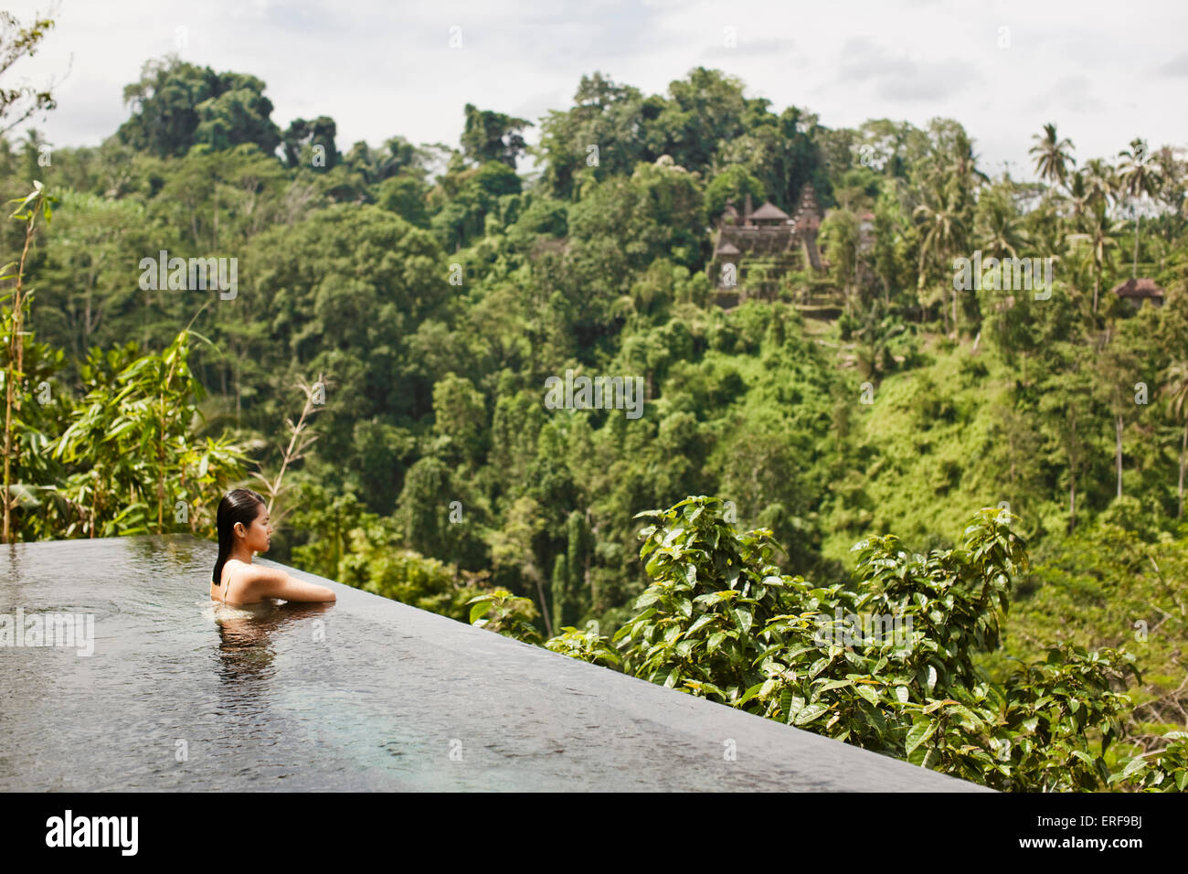 Les femmes asiatiques en piscine à débordement de la villa piscine privée à Ubud Hanging Gardens, Bali, Indonésie. La piscine à débordement donne sur la Banque D'Images