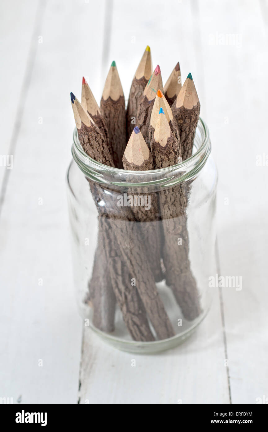 Groupe d'écorce covered crayons multicolores dans un bocal en verre Banque D'Images