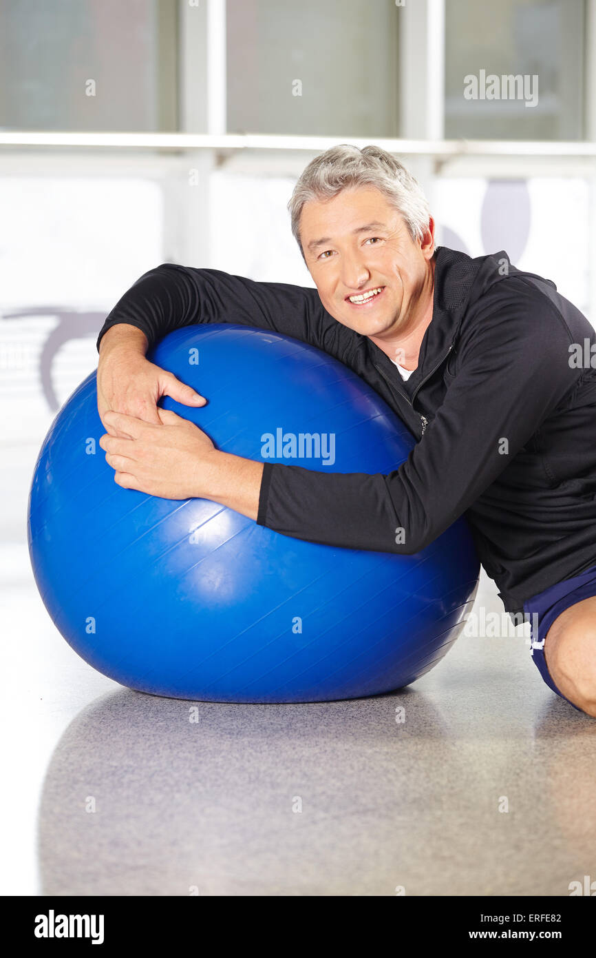 Happy senior man avec ballon de gymnastique faire retour de la formation dans un centre de remise en forme Banque D'Images