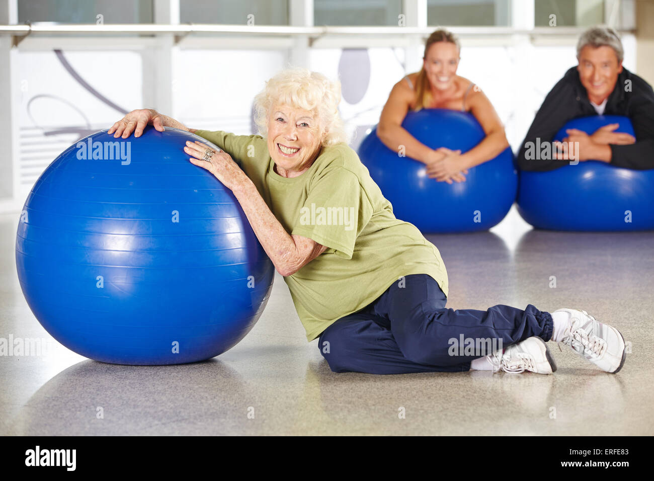Smiling senior woman sitting avec ballon de gymnastique dans un centre de réadaptation Banque D'Images