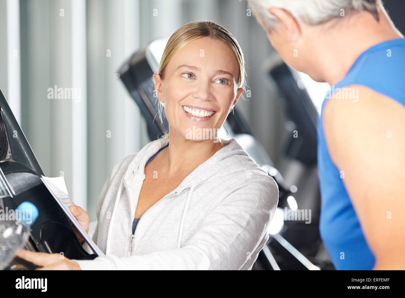 Femme fitness trainer aidant la haute sur tapis roulant dans un centre de remise en forme Banque D'Images