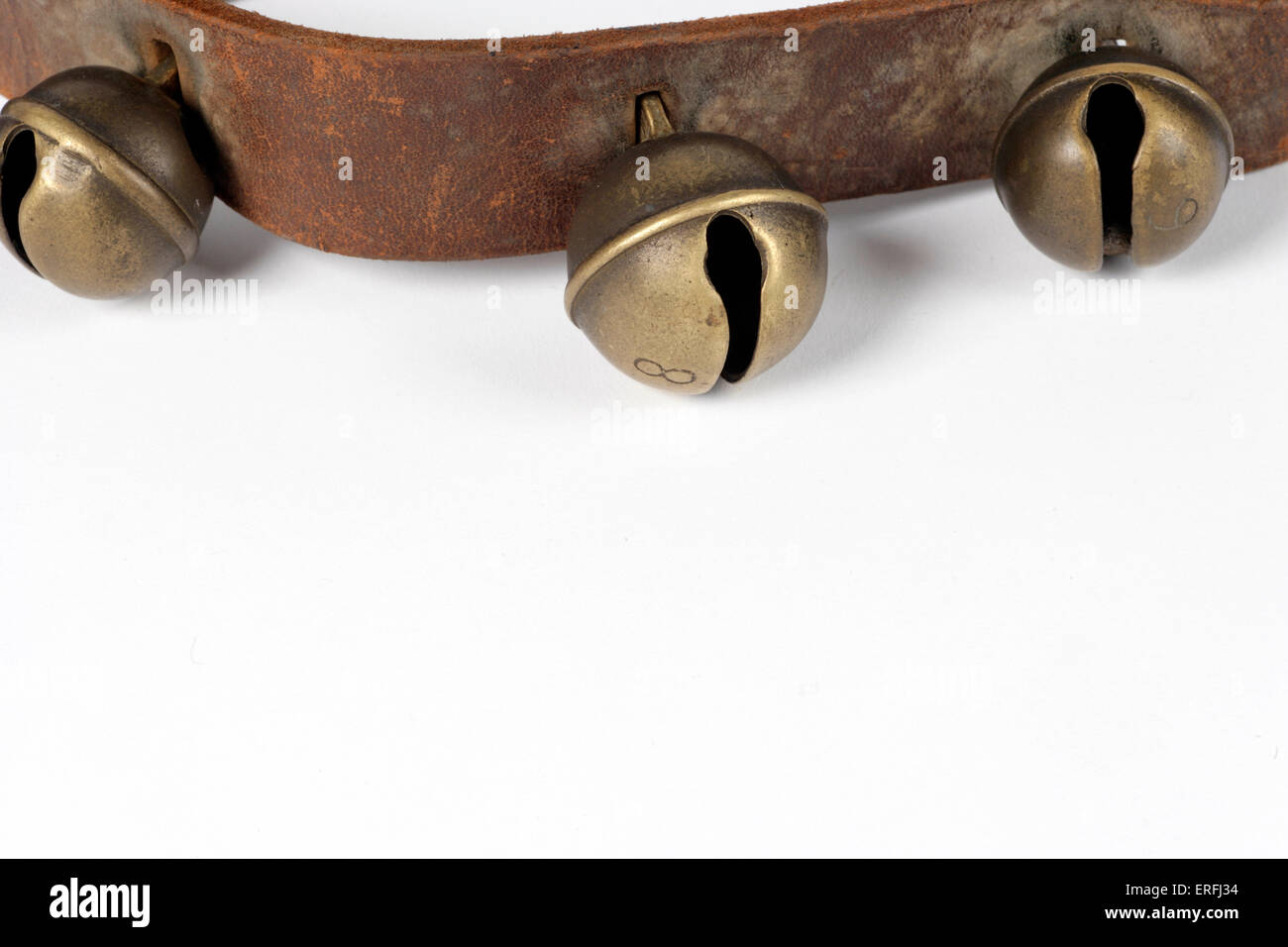 Sleigh bells sur un bracelet en cuir. Arrière-plan blanc. Banque D'Images