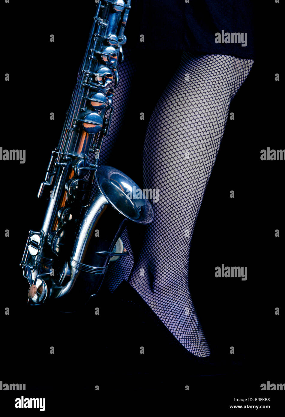 Saxophone Alto à côté d'une jambe de femme. Fond noir Banque D'Images