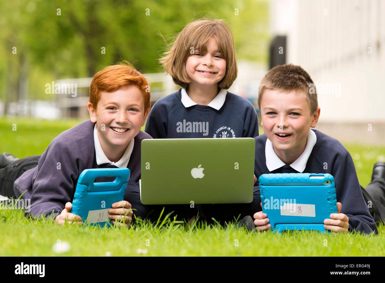 Les enfants de l'école l'apprentissage de la technologie et les ordinateurs alors que l'extérieur à l'aide d'ordinateurs portables. Banque D'Images