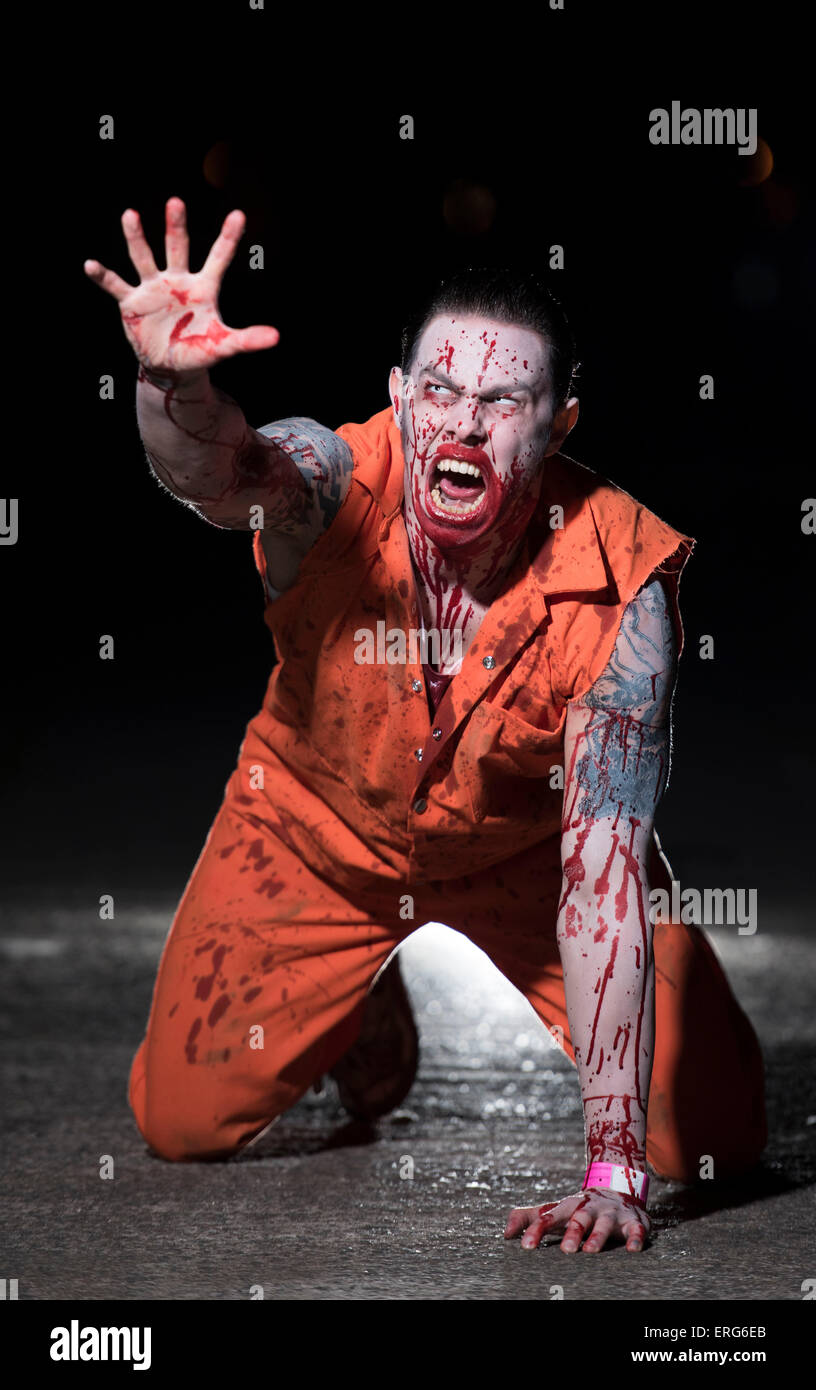 Une femme zombie, le visage éclaboussé de sang, sur ses mains et genoux. Banque D'Images