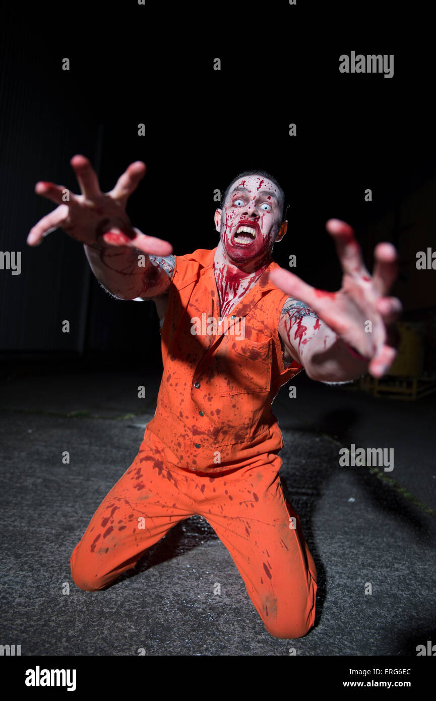 Une femme zombie, le visage éclaboussé de sang, sur ses genoux. Banque D'Images