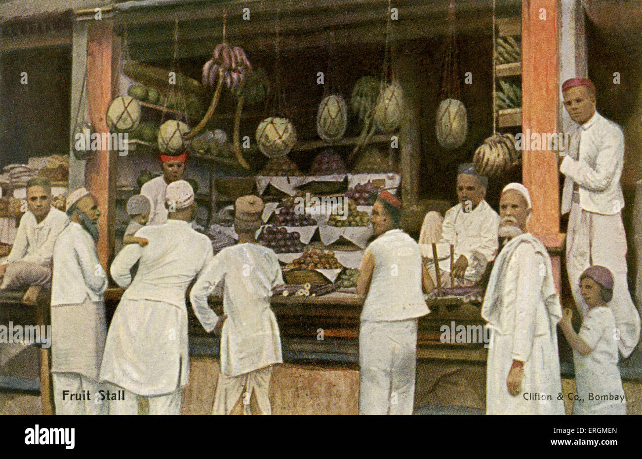 Étal de fruits dans l'Inde coloniale. Photographie colorisée du début du xxe siècle. Les hommes et les garçons à l'attente d'un étal de fruits, offrant Banque D'Images
