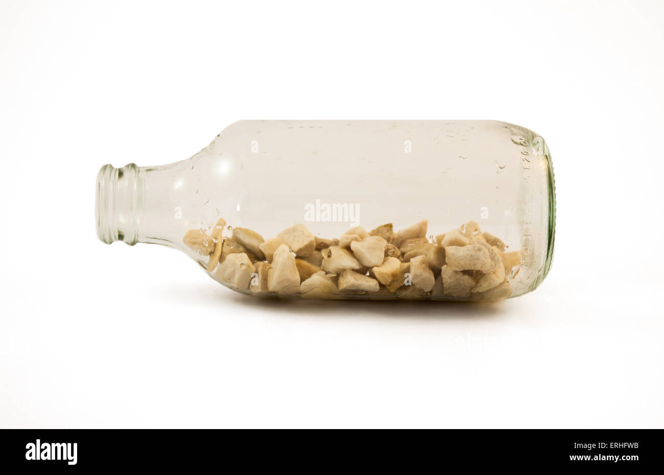 Une bouteille en verre remplie de petites pierres. Arrière-plan blanc. Banque D'Images