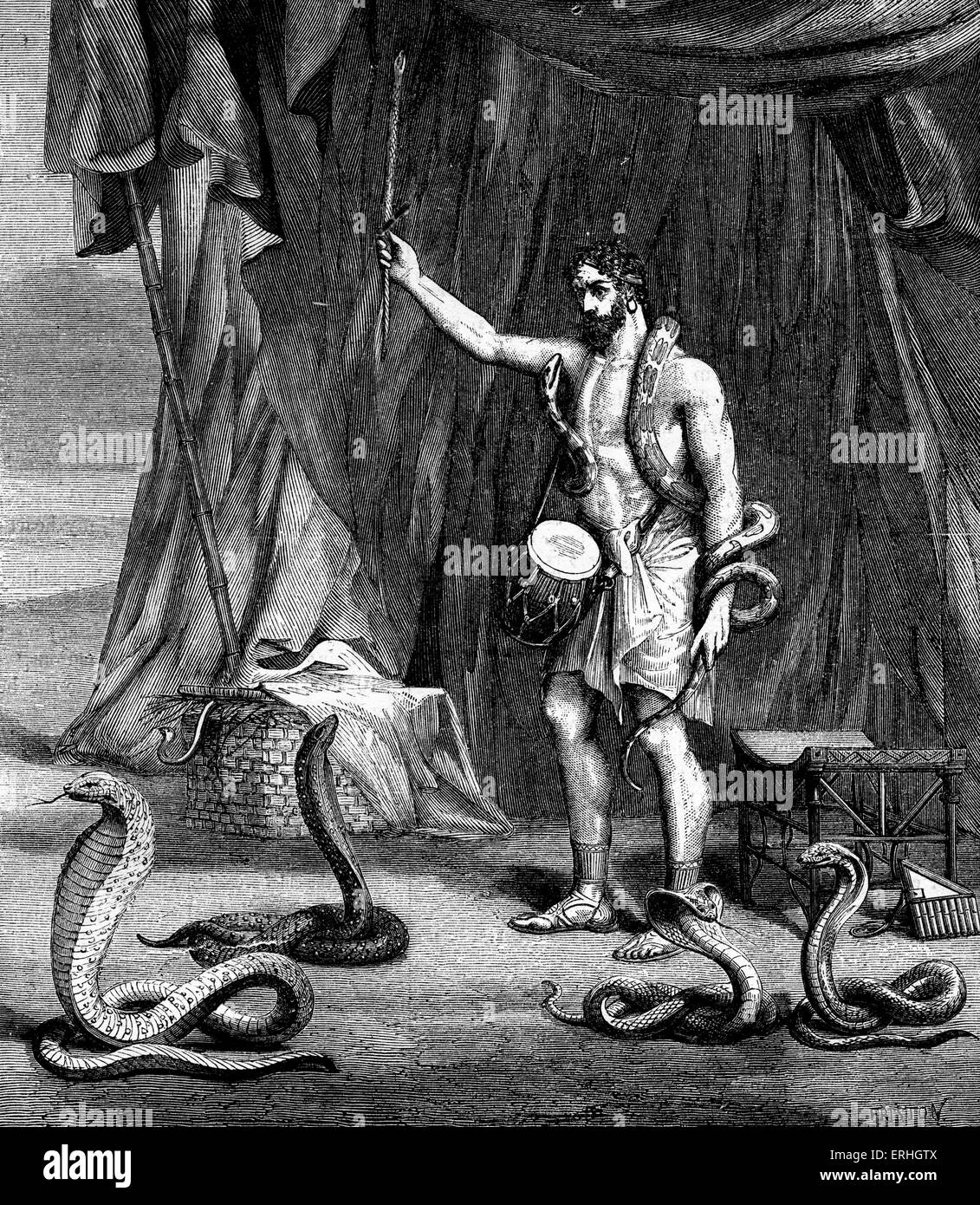 Charmeur de serpent à l'époque biblique entouré par des serpents et la tenue d'un tambour. Banque D'Images