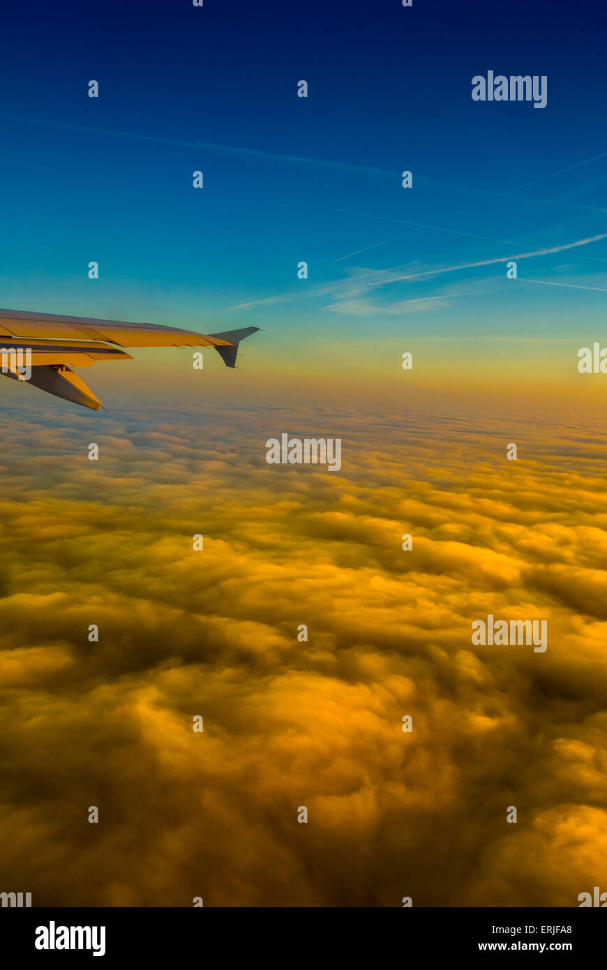 Vue depuis la fenêtre de l'avion au lever du soleil avec ciel bleu et nuages orange doré Banque D'Images
