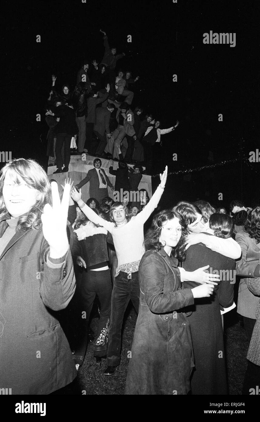 Une foule de jeunes gens heureux saluer la nouvelle année dans les esprits dans Broadgate, Coventry. Mais pour un couple c'est une occasion bien plus personnel. 1er janvier 1973. Banque D'Images