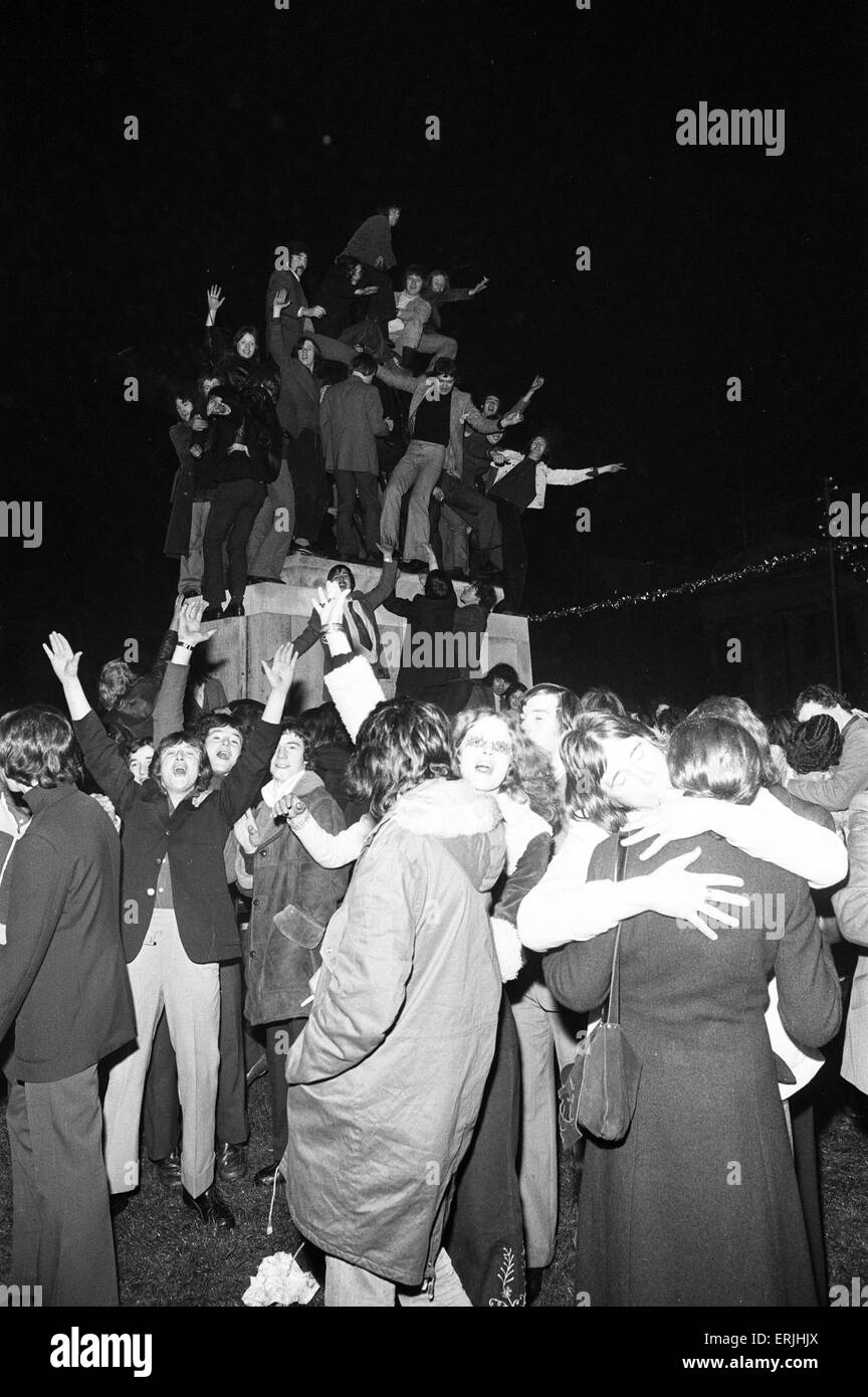 Une foule de jeunes gens heureux saluer la nouvelle année dans les esprits dans Broadgate, Coventry. Mais pour un couple c'est une occasion bien plus personnel. 1er janvier 1973. Banque D'Images