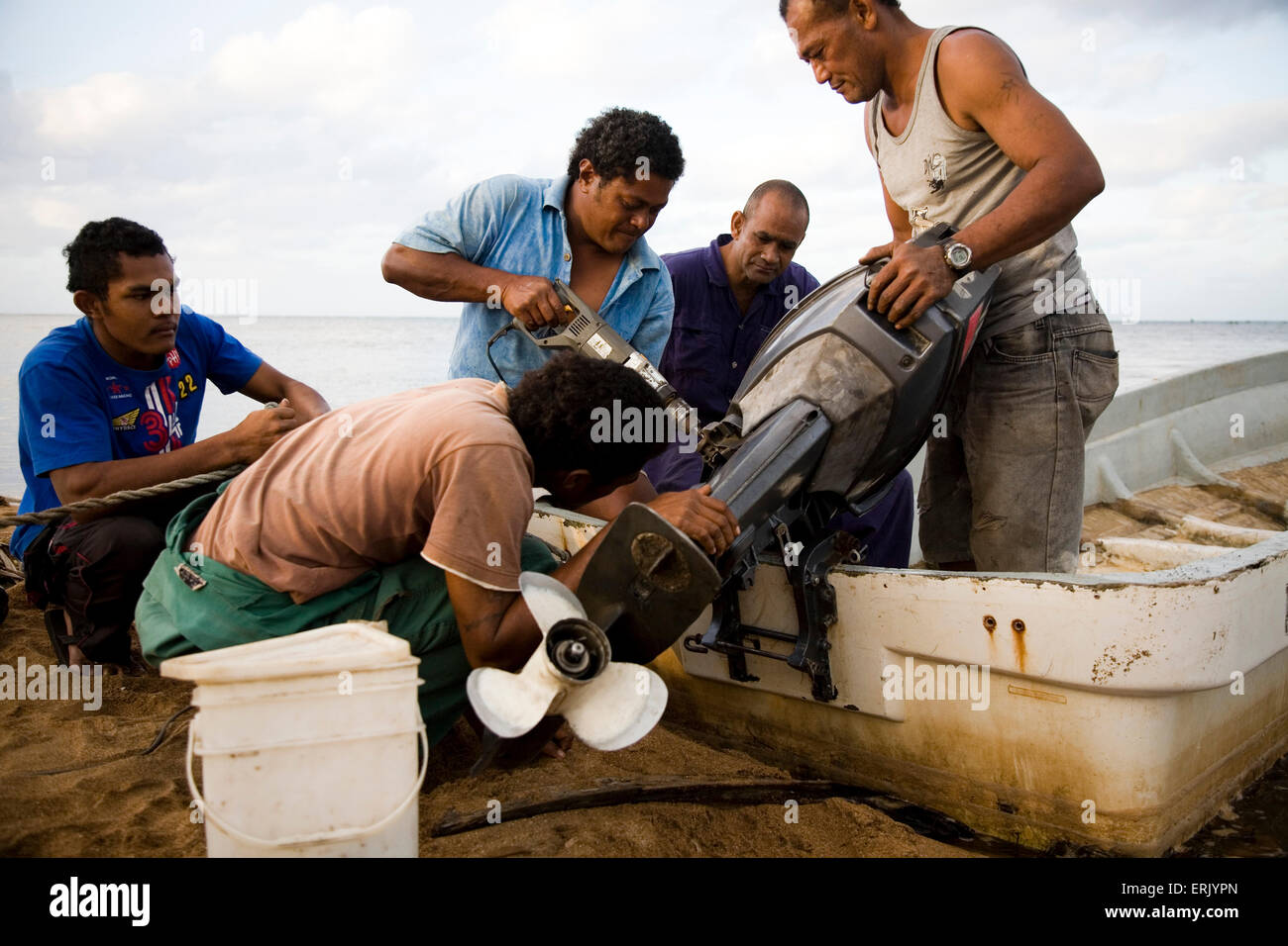 Un groupe d'hommes travaillent ensemble pour régler un moteur cassé. C'est l'un des deux moteurs les villages sont à pêcher le récif extérieur. Banque D'Images