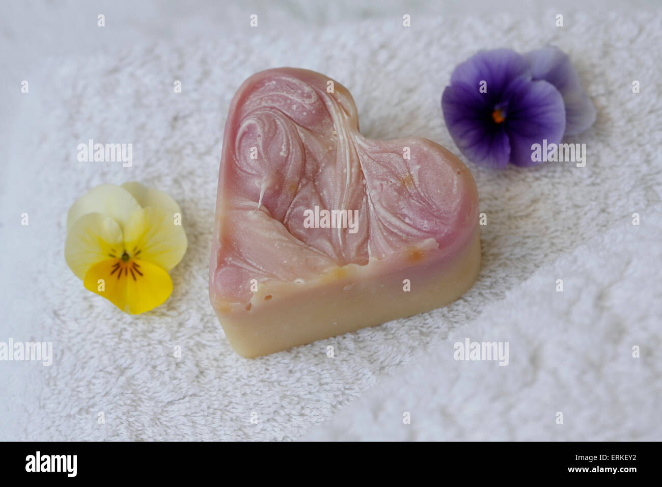 Savon en forme de coeur sur serviette éponge avec des fleurs de violettes cornu Banque D'Images