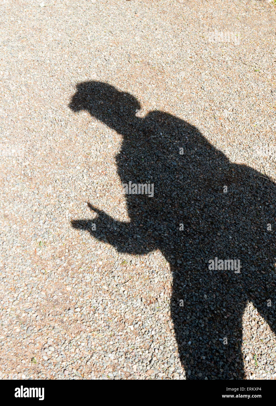 Ombre d'un homme portant un chapeau à large dans la lumière du soleil fait semblant de braquer un fusil avec ses doigts. UK Banque D'Images