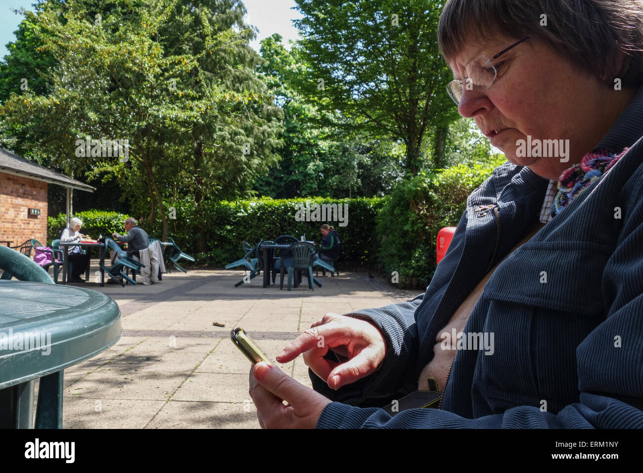 Les femmes utilisant spartphone at outdoor cafe Banque D'Images