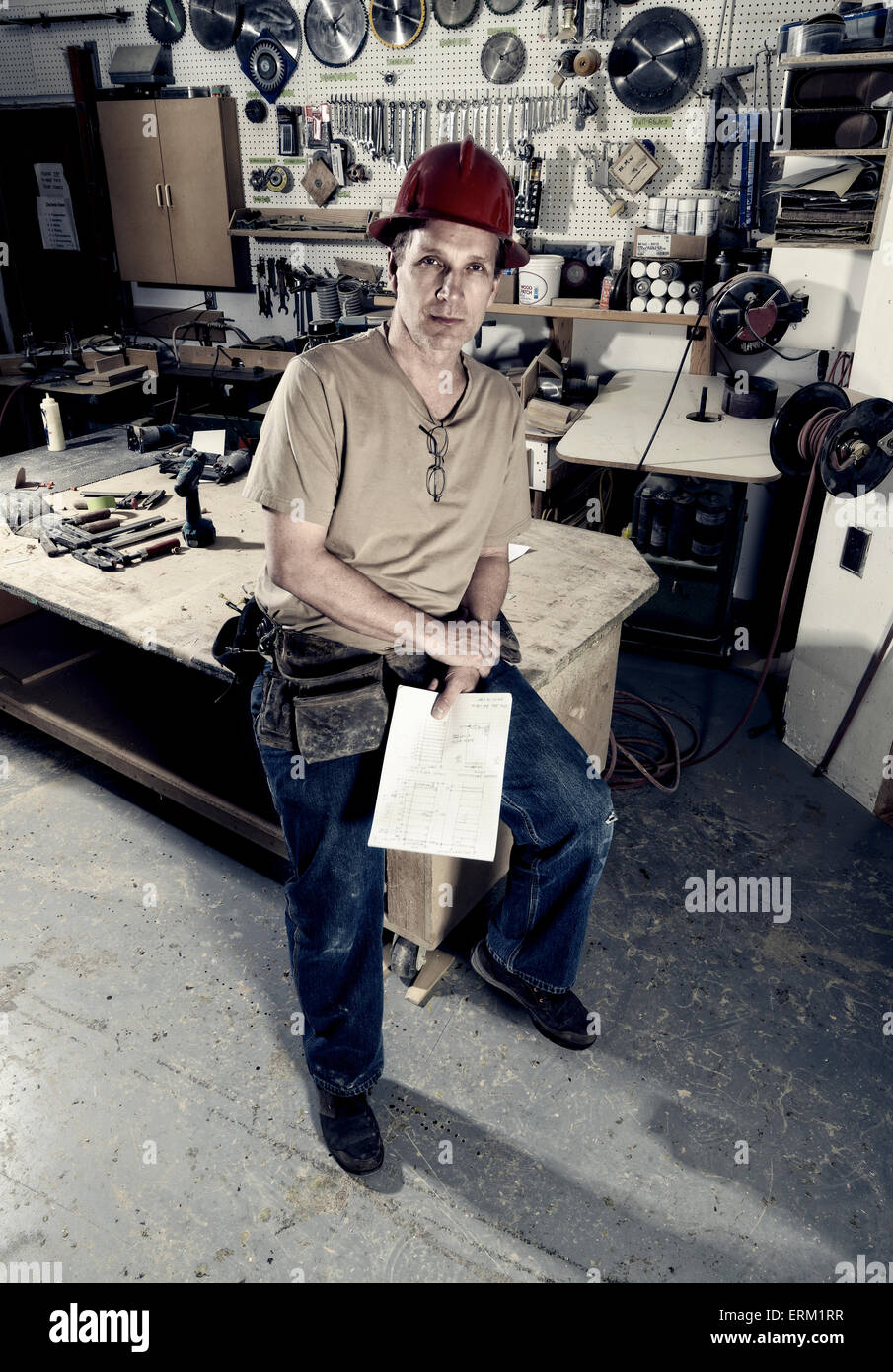 Un menuisier dans son atelier holding plans sur papier. Banque D'Images
