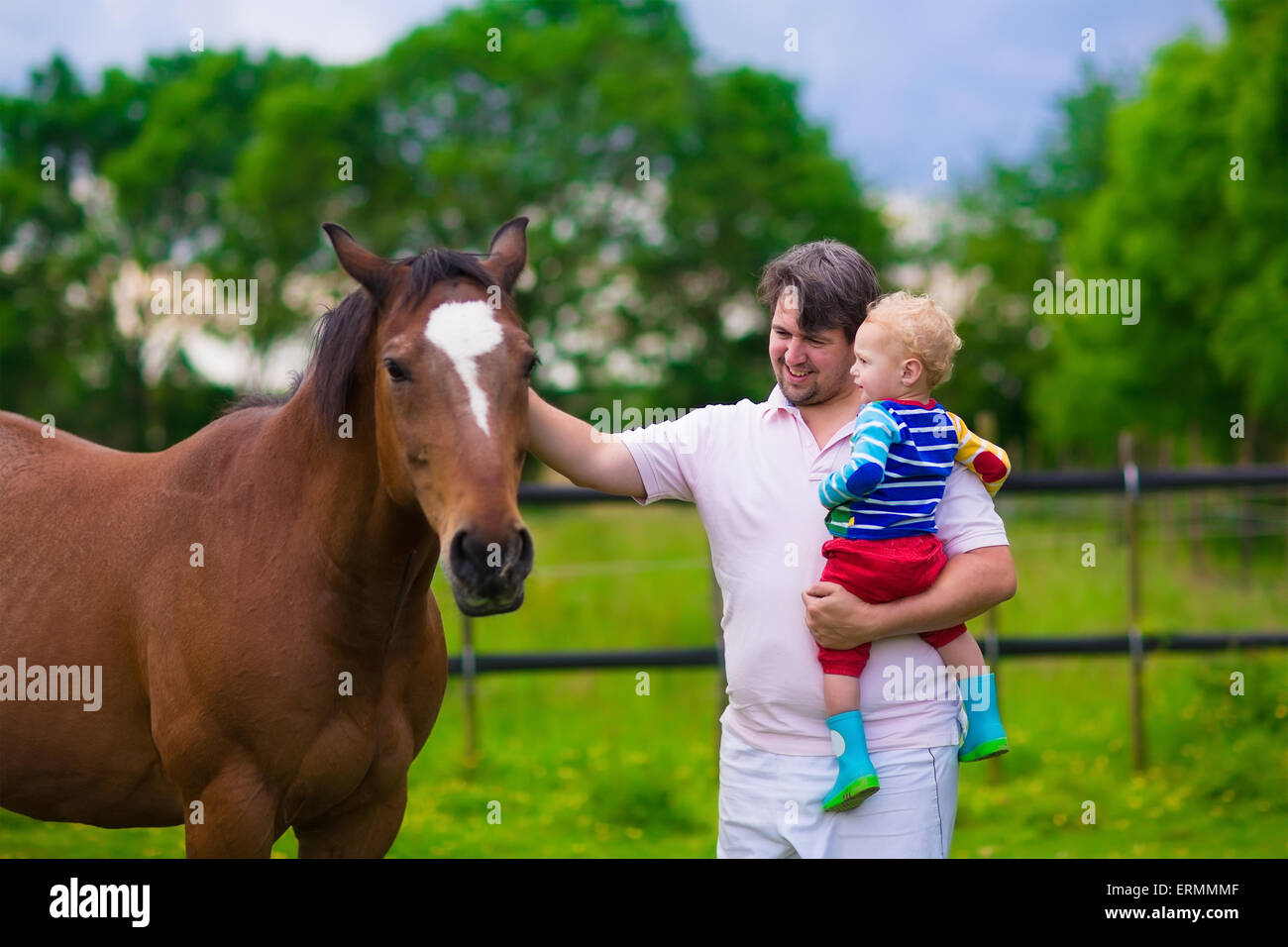 Sur une ferme familiale en été. Père et fils bébé nourrir un cheval. Plein air pour les parents et les enfants. Les enfants jouant avec des animaux. Banque D'Images