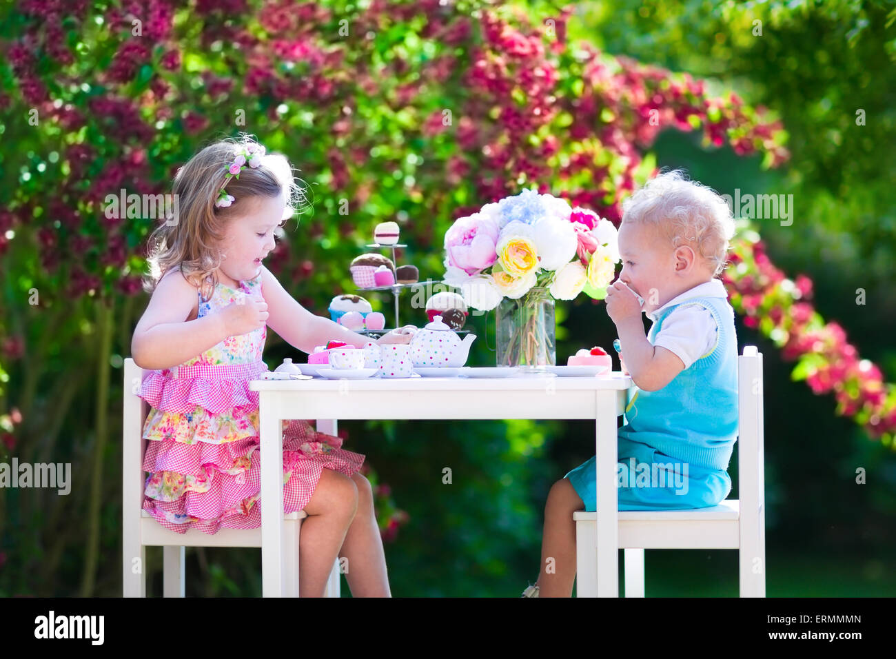 Tea garden party pour les enfants. L'anniversaire de l'enfant. Petit garçon et fille jouer piscine de boire du chocolat chaud et manger un gâteau. Banque D'Images