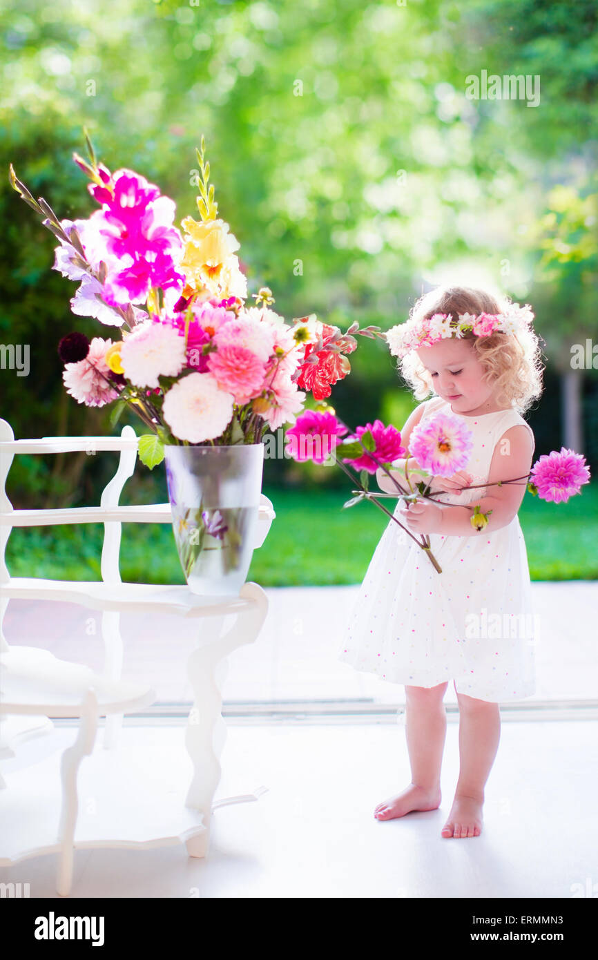 Petite fille d'organiser à la maison des fleurs dans un vase. Enfant jouant à l'intérieur. Kids Birthday party. Les enfants donnant fleur comme présent. Banque D'Images