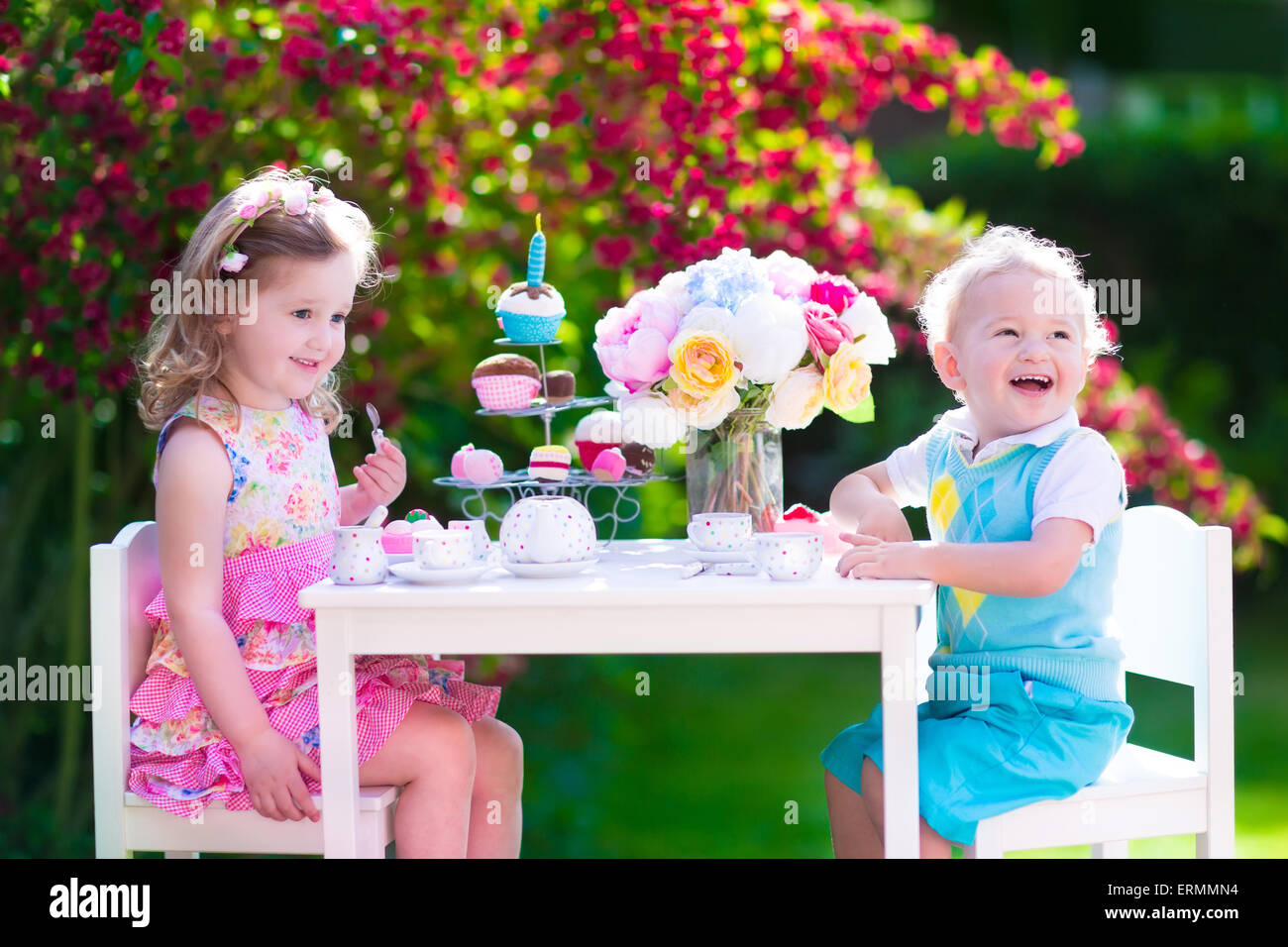 Tea garden party pour les enfants. L'anniversaire de l'enfant. Petit garçon et fille jouer piscine de boire du chocolat chaud et manger un gâteau. Banque D'Images