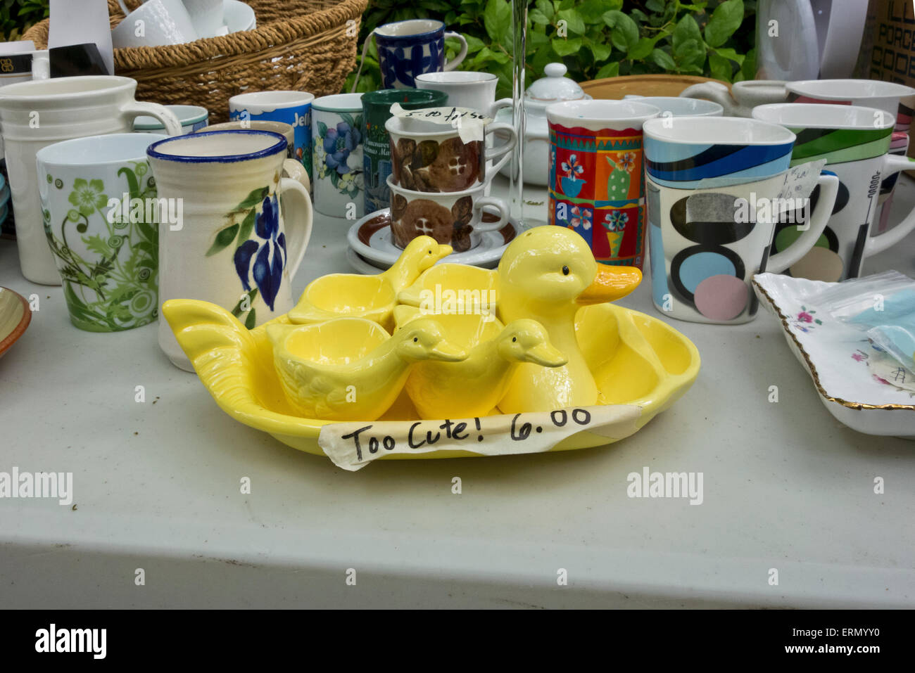 Ensemble d'oeuf Jaune mignon tasses en forme de canards, à vendre à une vente de garage avec d'autres tasses et ustensiles de cuisine. Banque D'Images