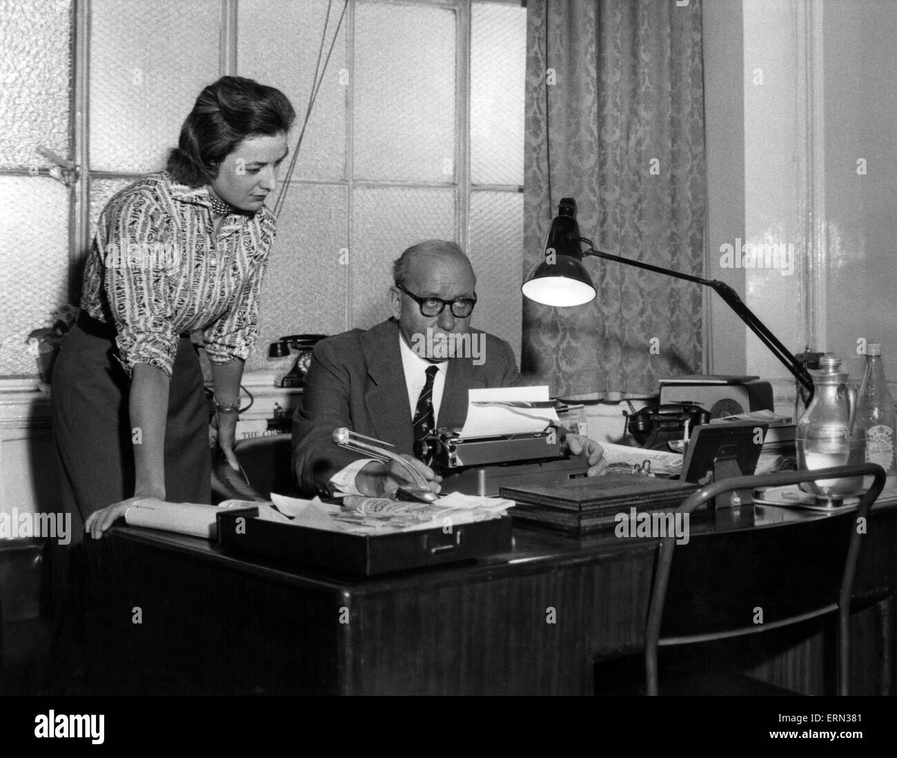 William Connor Journaliste Du Daily Mirror Qui A Ecrit Sous Le Pseudonyme De Cassandra En Compagnie Du Secretaire Derriere Le Bureau De Son Bureau Le 29 Juin 1960 Photo Stock Alamy