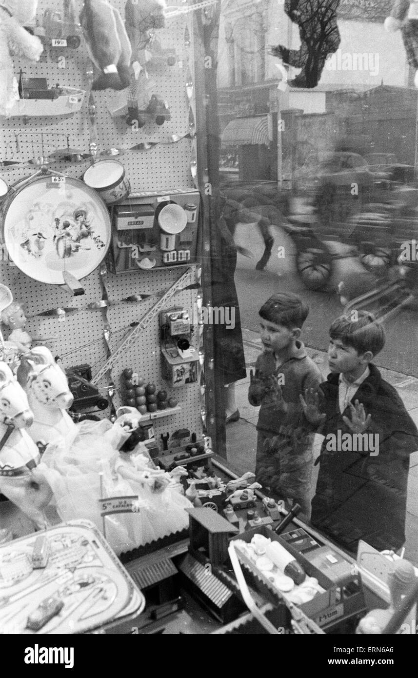 Regarder avec envie les enfants à des jouets en vitrine à Noël, le 16 décembre 1960. Banque D'Images