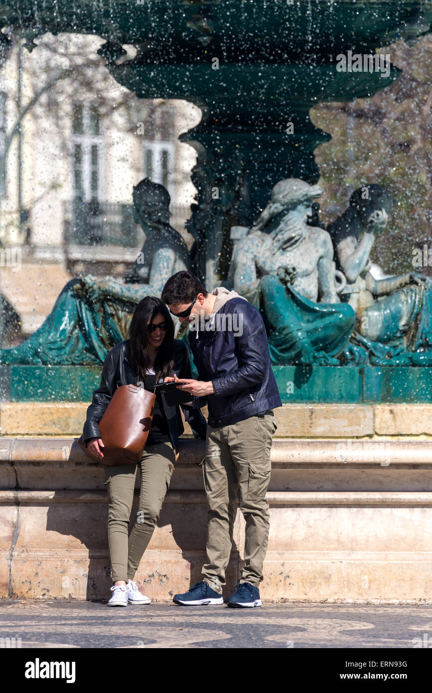 Young couple at Fountain.regarder des images sur tablette. Rosio square. Lisbonne Portugal. Banque D'Images