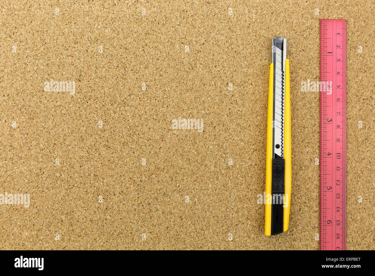Cutter et règle rouge sur le panneau de liège avec l'espace Banque D'Images
