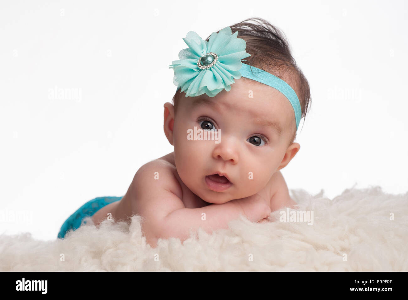 Un portrait d'une alerte, 3 mois bébé fille portant un bandeau de fleurs bleu turquoise. Elle est couchée sur le ventre, appuyée au Banque D'Images