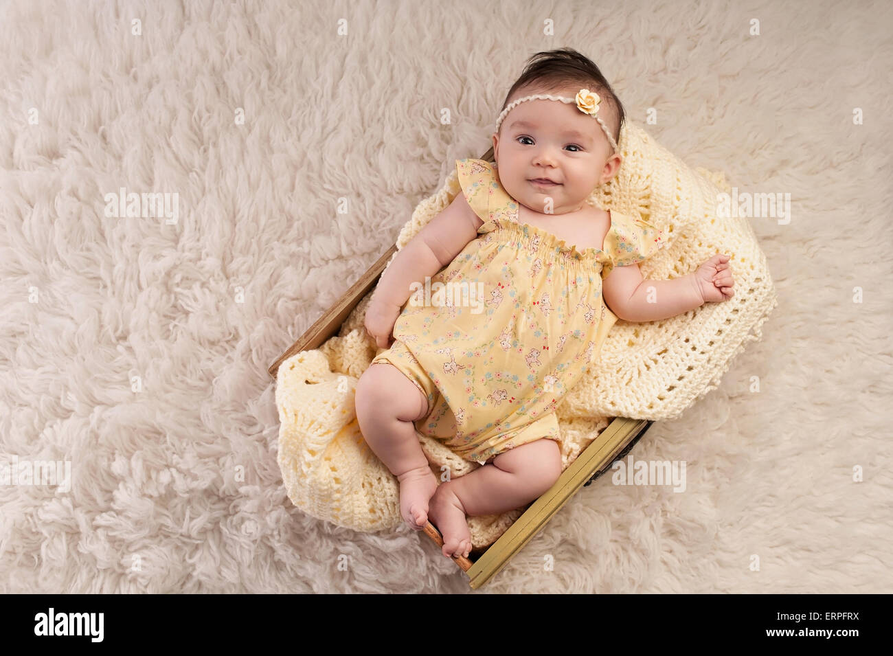 Souriant, trois mois baby girl wearing a vintage jaune inspiré, floral romper et couché dans un bac jaune. Banque D'Images