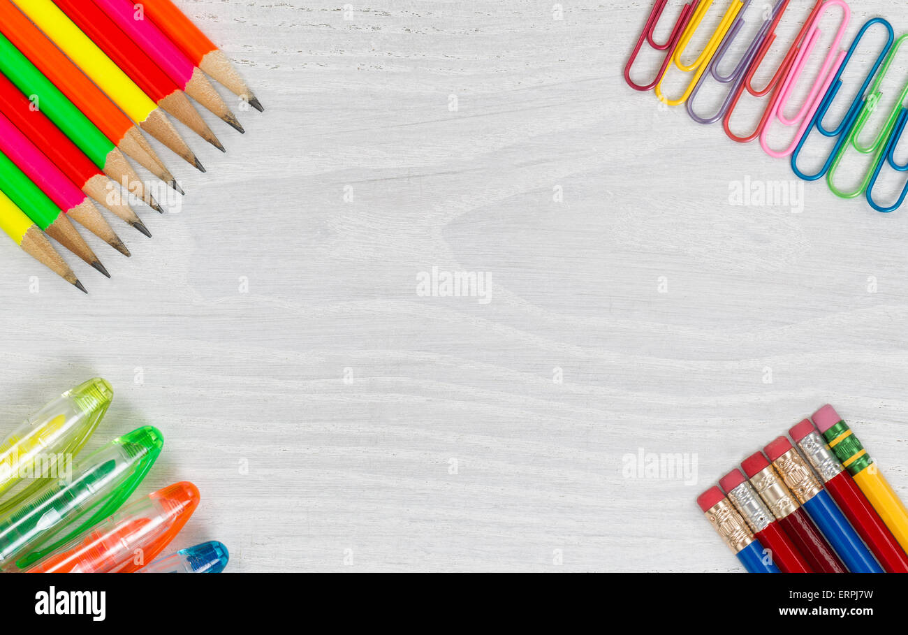 Bright colorful crayons, stylos et trombones sur tous les coins de bureau en bois blanc. Vue d'angle élevée en format horizontal. Banque D'Images