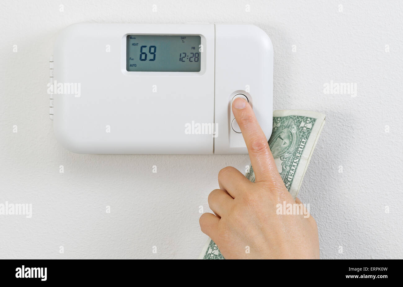 Image main de femme libre de réglage du thermostat de chauffage avec de l'argent monnaie partielle à Palm. Banque D'Images
