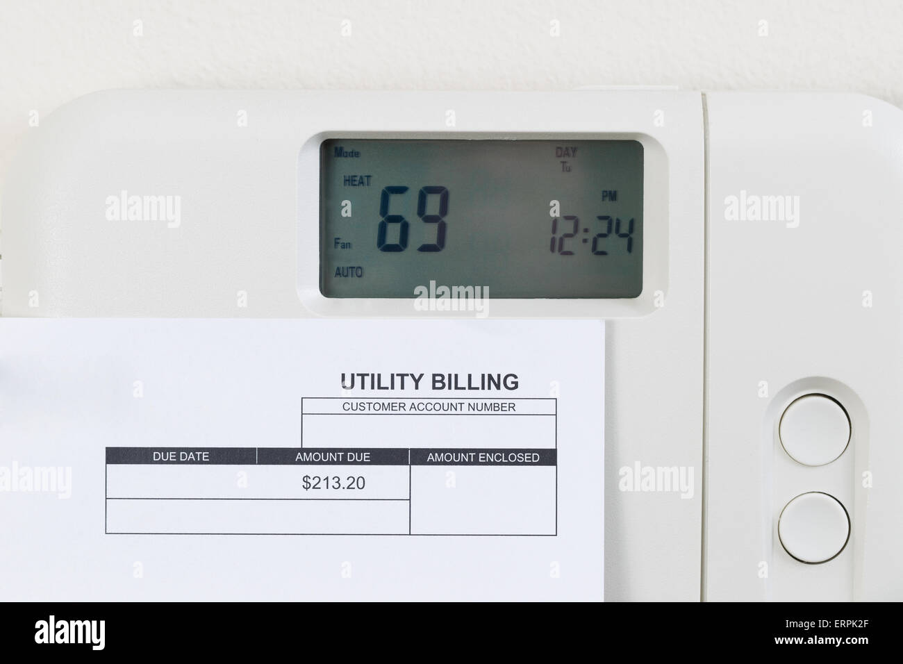 Close up of home thermostat de chauffage avec vue partielle d'une facture sur le mur. Banque D'Images